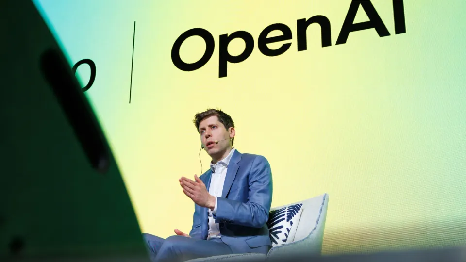 OpenAI CEO Sam Altman speaks at an industry event in front of the OpenAI branding.